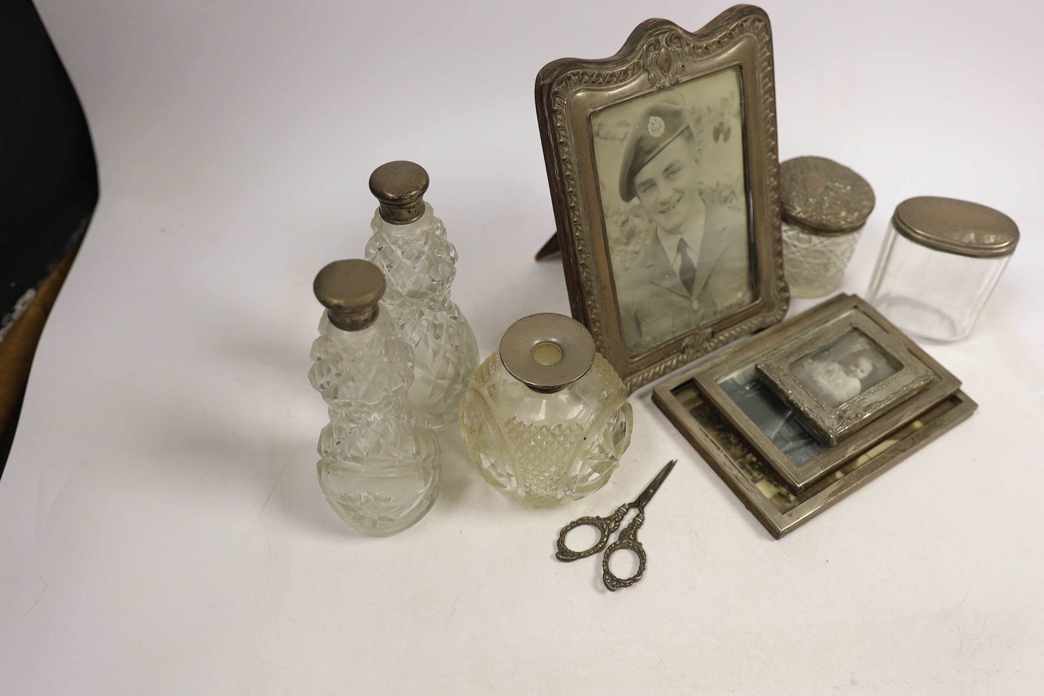 Four assorted early 20th century silver mounted photograph frames, largest 19.5cm (a.f.) five assorted silver mounted glass toilet jars and a small pair of silver handled scissors.